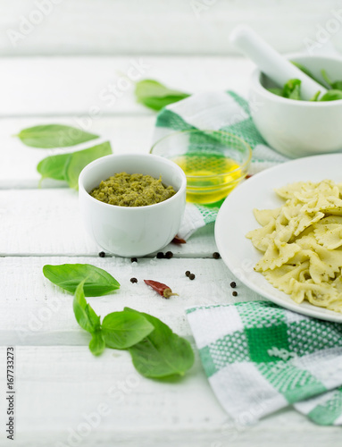  Farfalle pasta with pesto genovese (basil sauce) on white rustic wooden table. Italian cuisine