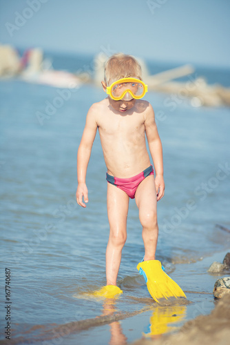 Little boy with snorkel by the sea. Cute little kid wearing mask and flippers for diving at sand tropical beach. Ocean coast.