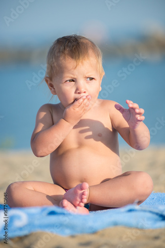 Baby playing with toys on the sandy beach near the sea. Cute little kid in  sand on tropical beach. Ocean coast.