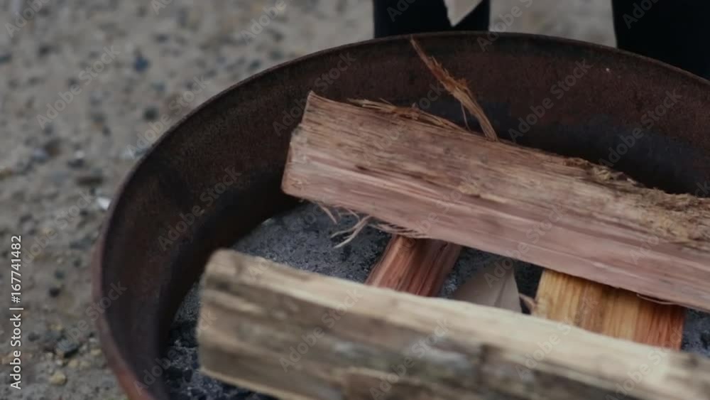 Closeup Of Camper Ripping Up Scrap Paper And Adding It To Fire Pit Closeup Of Camper Ripping Up Scrap Paper And Adding It To Fire Pit