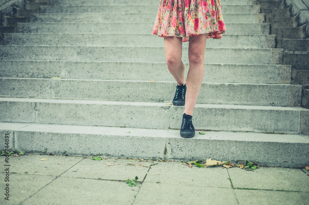 Legs of young woman walking down stairs in city Legs of young woman walking down stairs in city