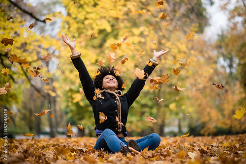 Joyous teen playing with dry maple leaves