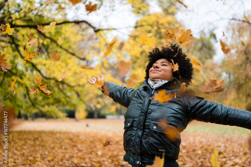 Smiling woman in park, arms outstretched.