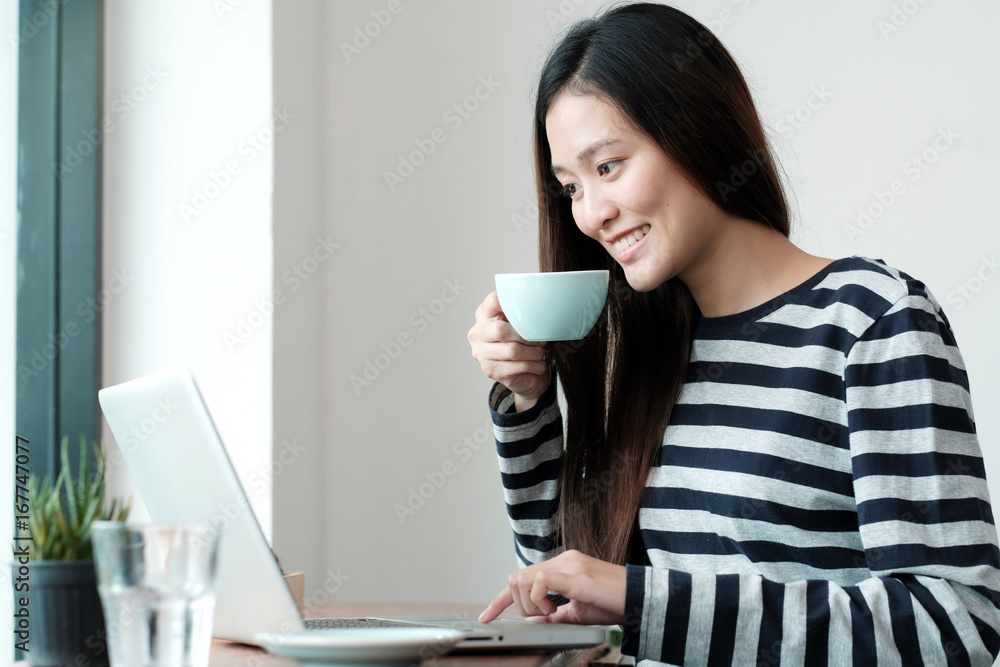 Young asian woman using laptop computer and drinking coffee at cafe background, people and technology, lifestyles Young asian woman using laptop computer and drinking coffee at cafe background, people and technology, lifestyles