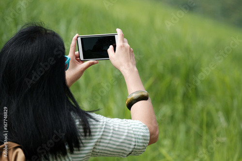 Woman traveler using smart phone to shoot green landscape view background, travel and lifestyle concept