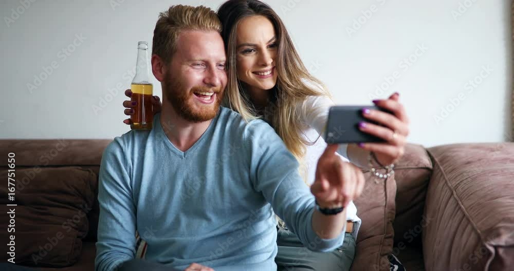 Young couple in apartment looking at smart phone and smiling Young couple in apartment looking at smart phone and smiling