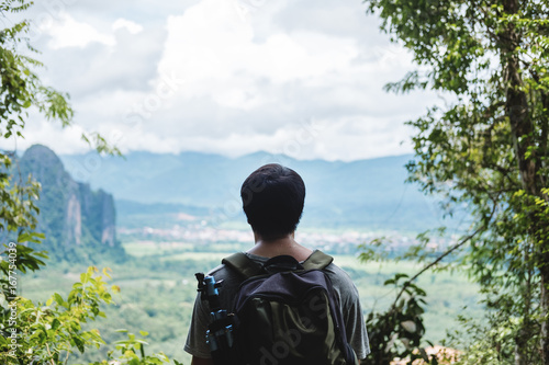 Young photographer with backpack enjoying beautiful landscaped nature view on the way to top of mountain in Laos, Traveling leisure activity hiking to sightseeing spot © SasinParaksa