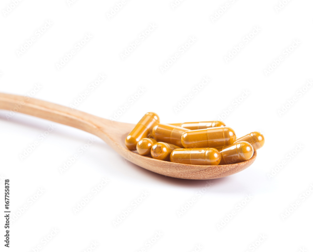 close up the Turmeric capsule in wooden spoon on white close up the Turmeric capsule in wooden spoon on white