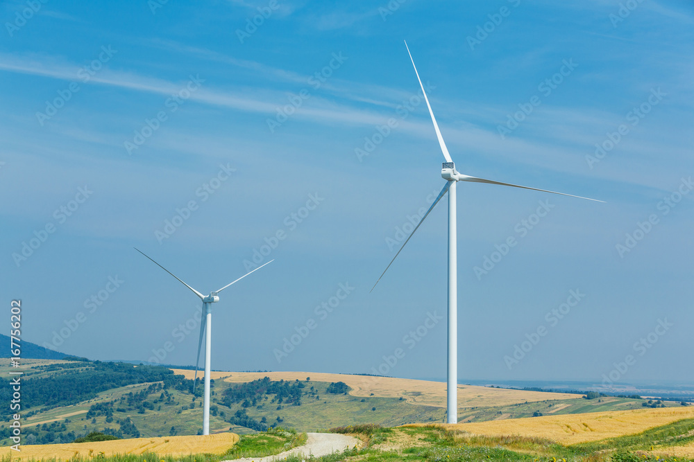 Wind turbines standing on a heels among fields