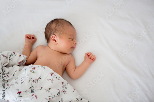 Quadro em tela Beautiful newborn baby boy in bed. Infant lying down in bed
