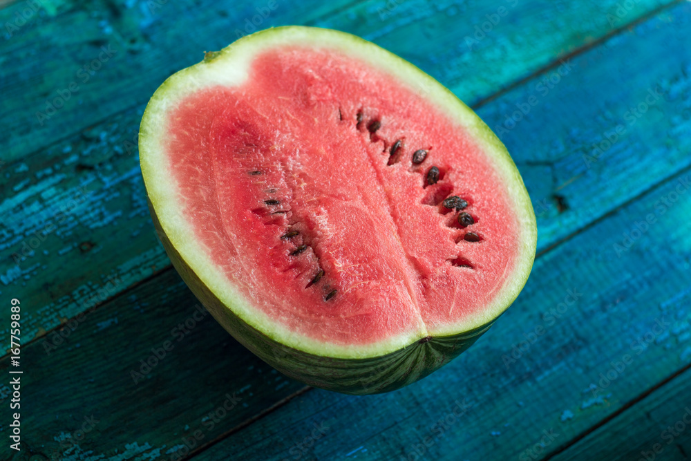 half of watermelon on a bright blue wooden background half of watermelon on a bright blue wooden background
