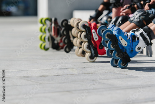 Feet of rollerbladers wearing inline roller skates sitting in outdoor skate park, Close up view of wheels befor skating photo
