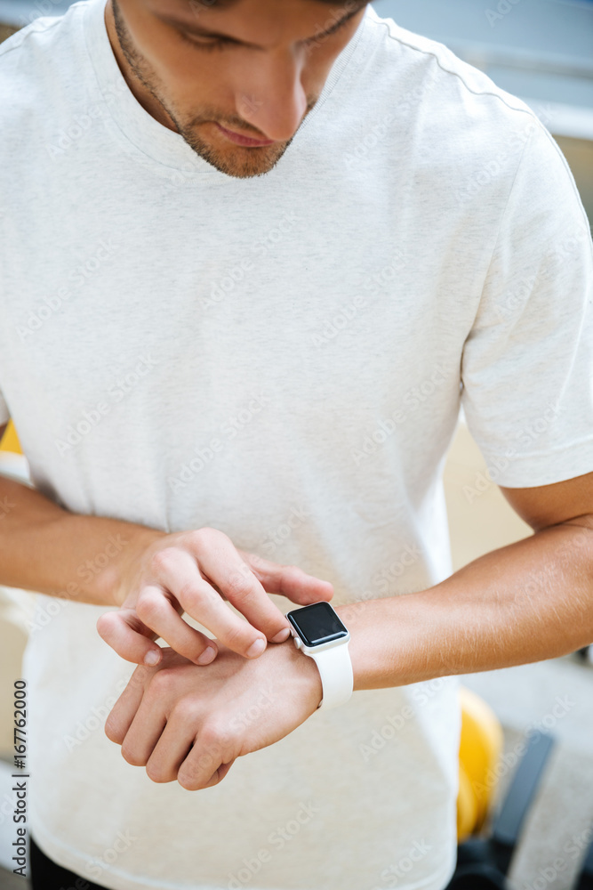 Obraz premium Concentrated young sports man looking at watch
