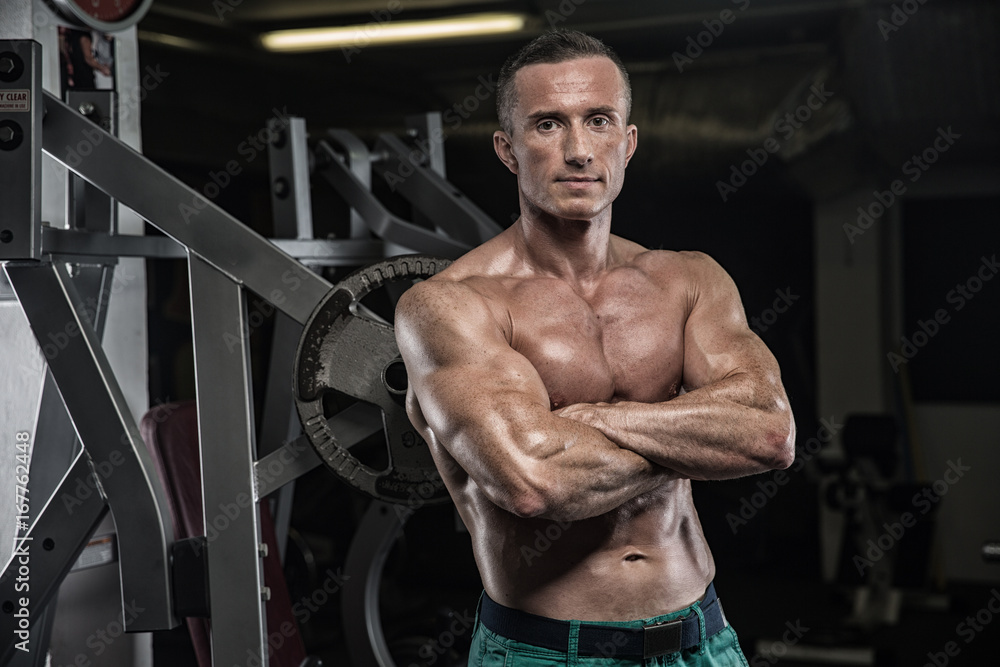 Handsome man with big muscles, posing at the camera in the gym Handsome man with big muscles, posing at the camera in the gym