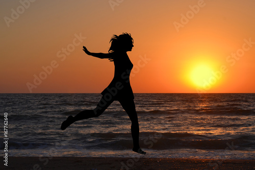 Happy woman jumping in sea sunrise