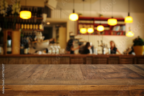 Image of wooden table in front of abstract blurred restaurant lights background photo