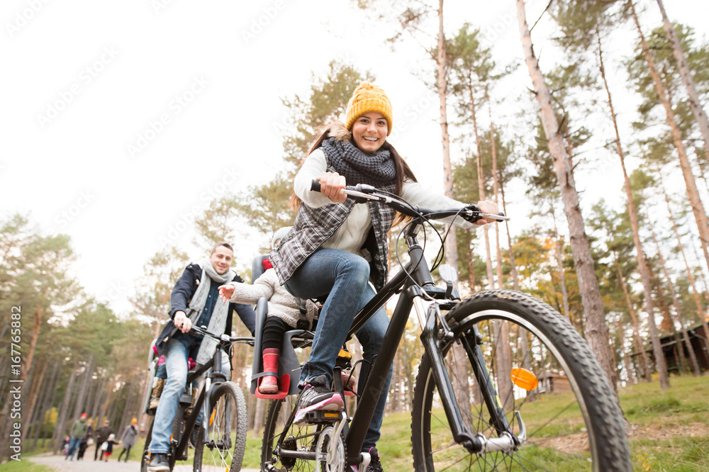 Young family in warm clothes cycling in autumn park