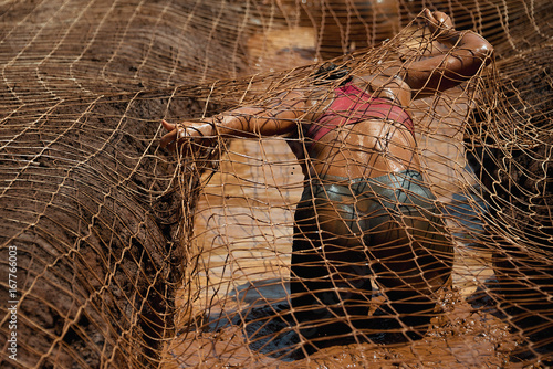 Mud race runners.Woman covered with mud fighting to get out of a net in the obstacle race photo