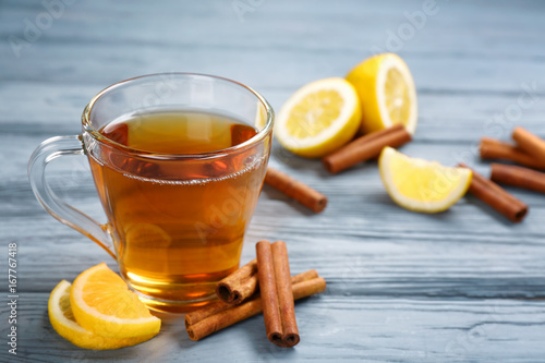 Cup with aromatic hot cinnamon tea and lemon on wooden table