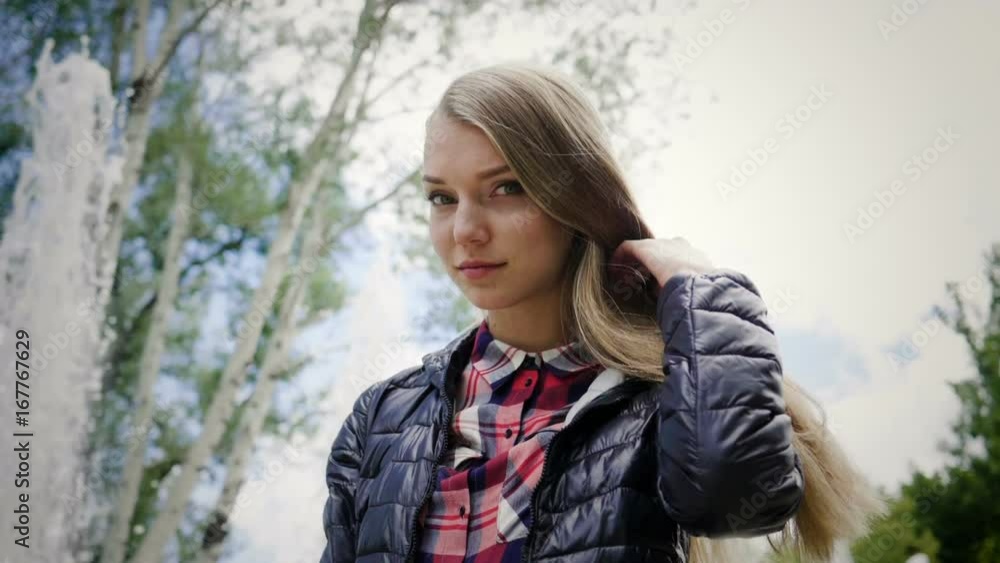 Portrait of pretty young woman with straight blonde hair in the background of a fountain. 4K Portrait of pretty young woman with straight blonde hair in the background of a fountain. 4K