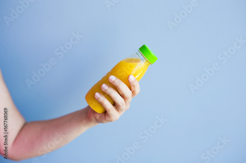 Close-up of female hand holding a bottle with juice