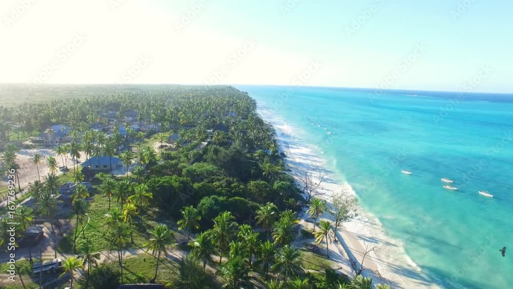 Aerial view of tropical paradise beach with white sand and turquoise crystal clear water of blue lagoon at sunset, a lot of palm trees on shore - Paje, Zanzibar, Tanzania, Africa, Indian Ocean, 4k UHD Aerial view of tropical paradise beach with white sand and turquoise crystal clear water of blue lagoon at sunset, a lot of palm trees on shore - Paje, Zanzibar, Tanzania, Africa, Indian Ocean, 4k UHD
