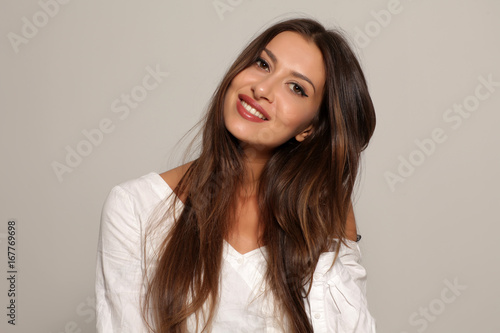 seductive and smiling young woman on a gray background
