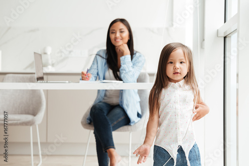 Little cute asian girl playing while her mother is working