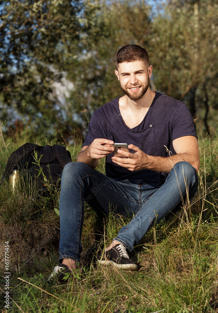 Fototapeta premium Man on hike in nature using phone