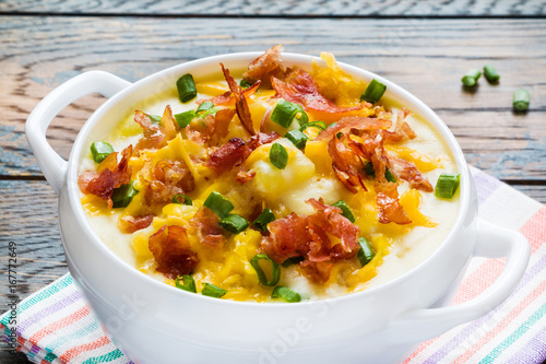 Easy homemade cheesy potato soup with bacon in a white bowl on the wooden rustic table.