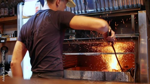 Cowboy cook stirs the coals in the grill