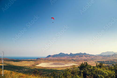 Paraglider flying over a valley.