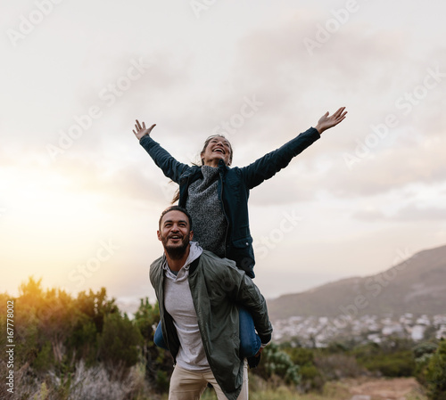 Young man piggybacking his girlfriend in countryside