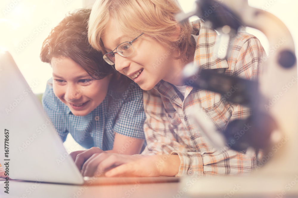 Positive delighted teenagers working with laptop Positive delighted teenagers working with laptop