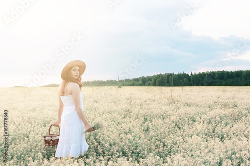 Girl in white dress in a field of yellow flowers blossoming