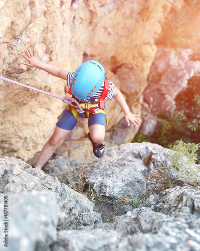 a little boy climbs on cliff. top view