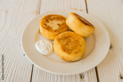 Cottage cheese cakes on plate with sour cream