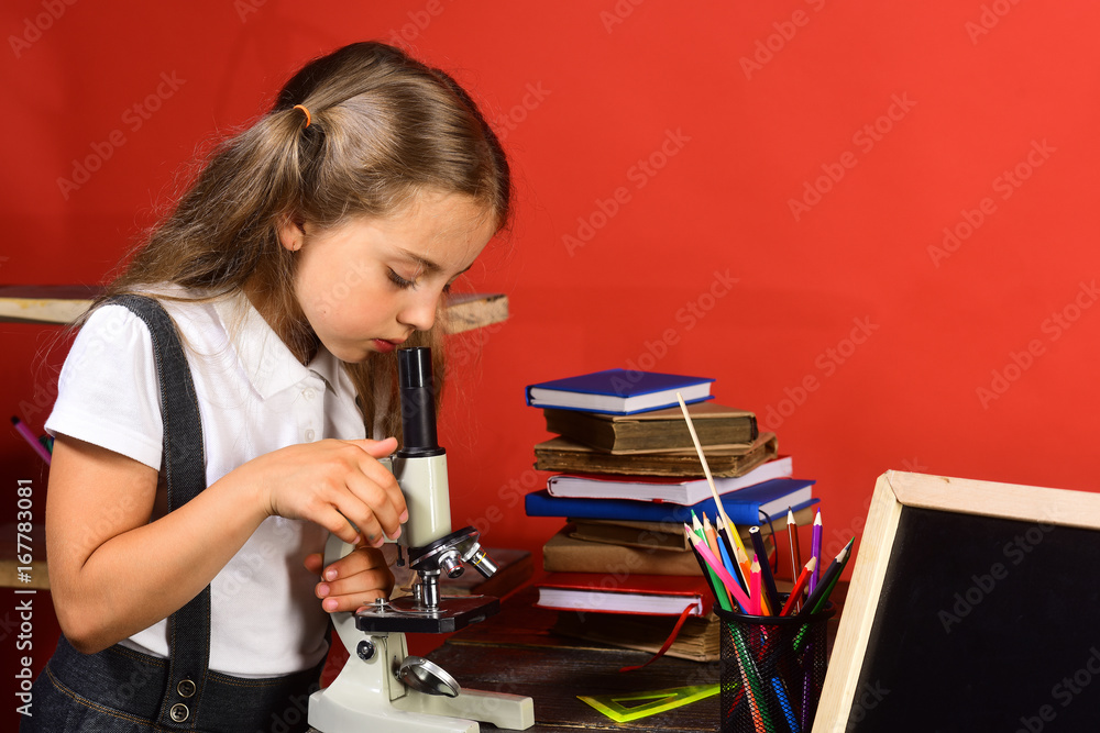 Kid with school and lab supplies on red wall background
