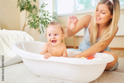 Fotografie Baby bathing in the bathroom with his mother