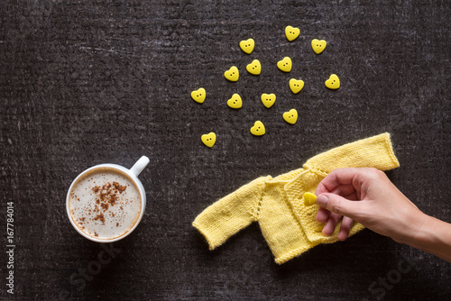 Coffee, knitting and hand with button on black photo