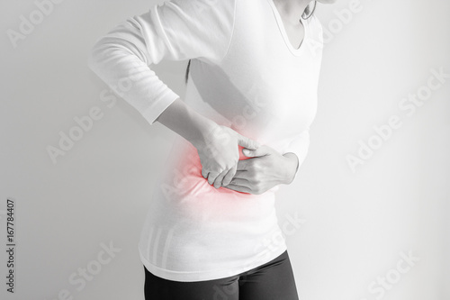 Woman stomachache on gray wall background.