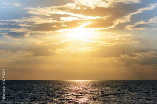 Sunset (dawn) of the sun and sunbeams over the sea (ocean). Summer sea background.