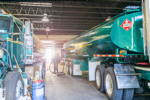 Worker refuelling biofuel tankers in biofuel plant depot