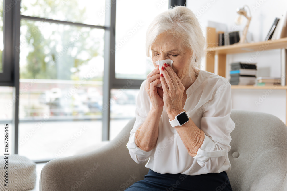 Unhappy elderly woman sneezing Unhappy elderly woman sneezing