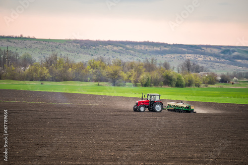 Tractor  agrimotorworking the ground. Different parts of the field, green yellow, black. Beautiful sky, hilly terrain. Season of agricultural works.   © Ann Stryzhekin