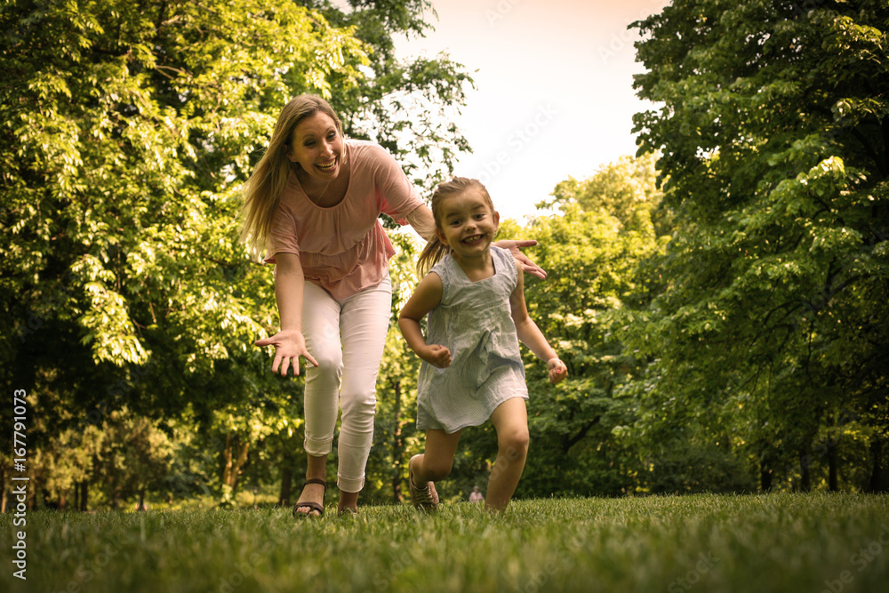 Mother and daughter running trough meadow. Mother chases her daughter. Mother and daughter running trough meadow. Mother chases her daughter.