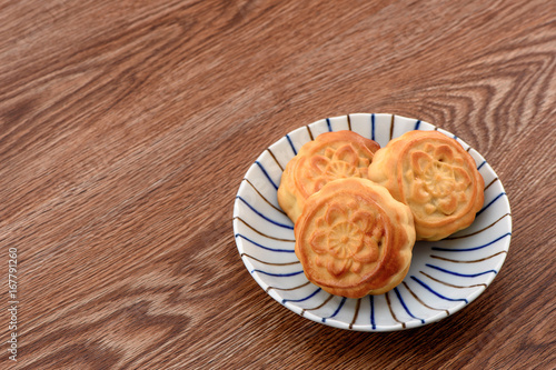 Chinese moon cake -- food for Chinese mid-autumn festival on a colorful plate isolated on wooden background