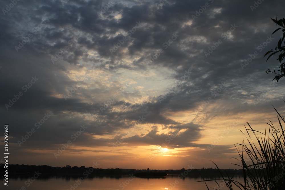 Fototapeta premium Beautiful sunset cloudy blue bright sky and golden light with silhouette tree reflect on calm water in the lake