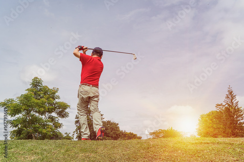 Man playing golf on a golf course in the sun 