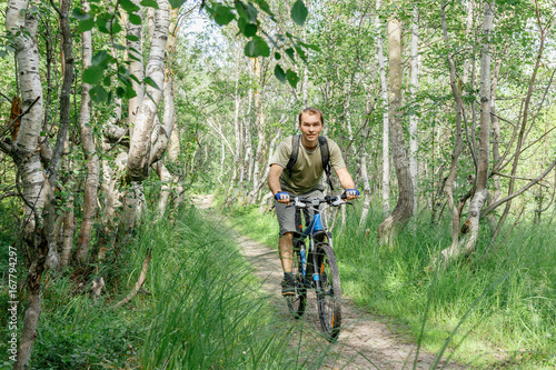 a young man rides through a forest path on a bike